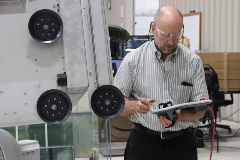 Man holding tablet next to suction cups of a robot